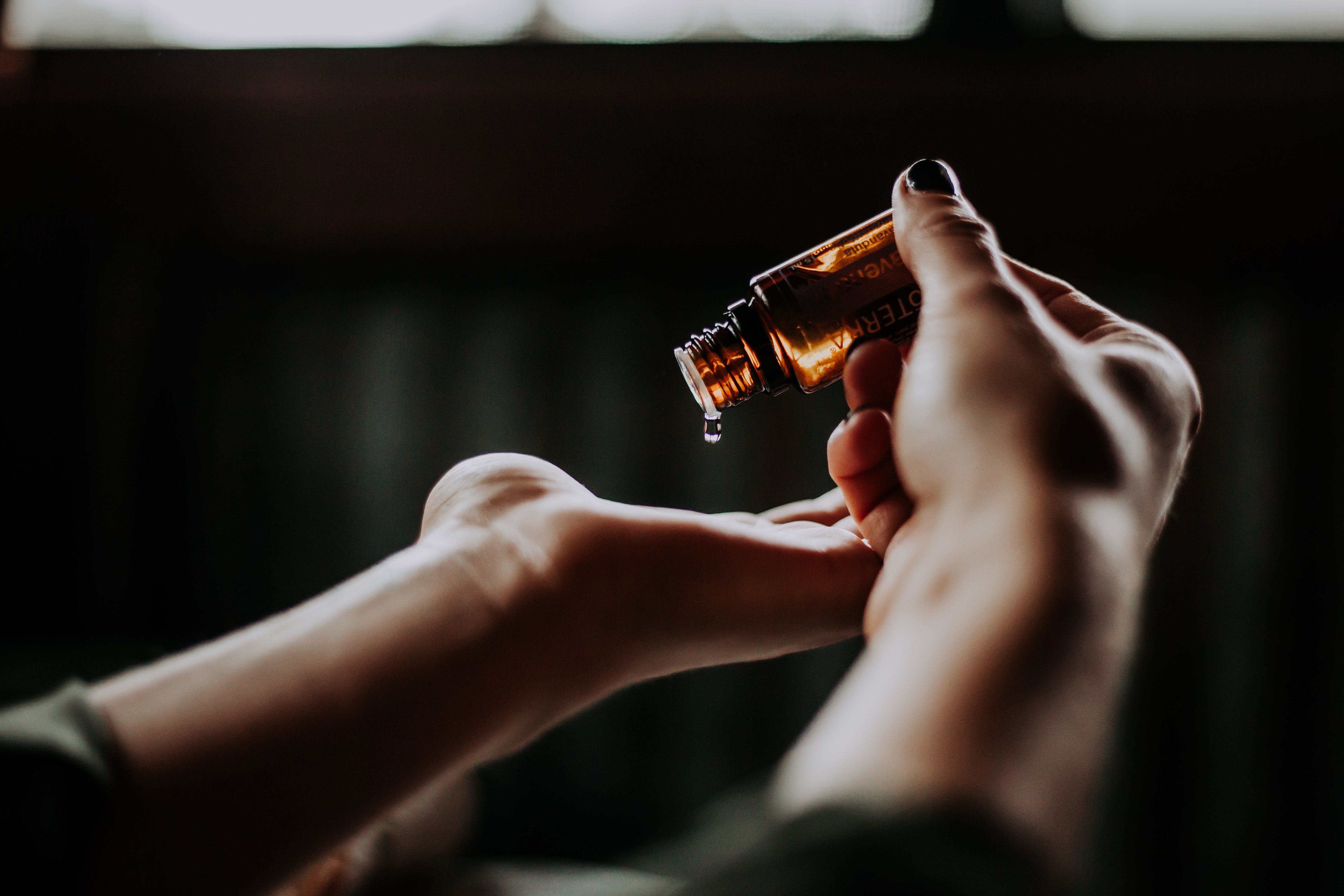an essential oil dropper dripping contents onto a female's hand