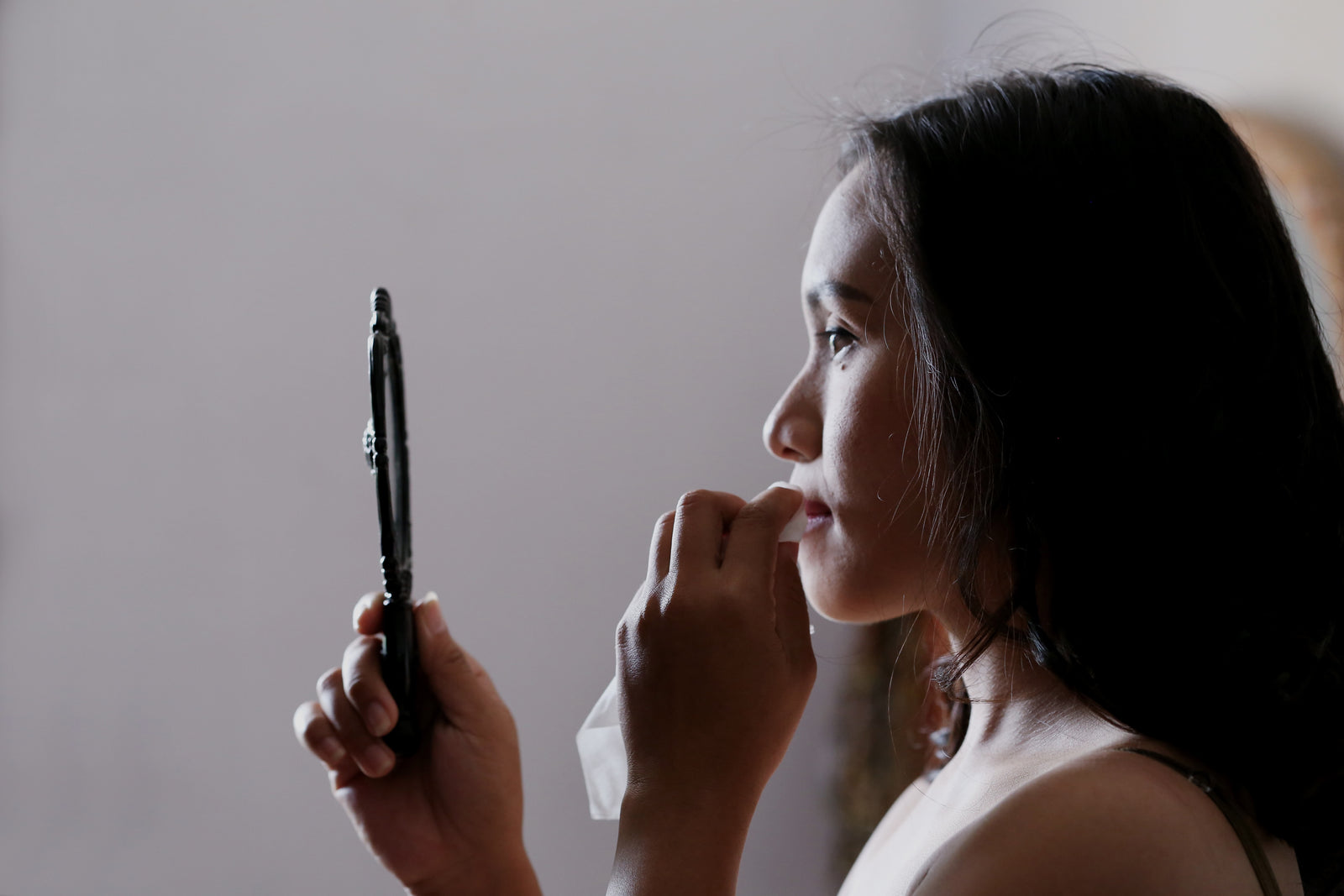 a woman taking her makeup off in the mirror